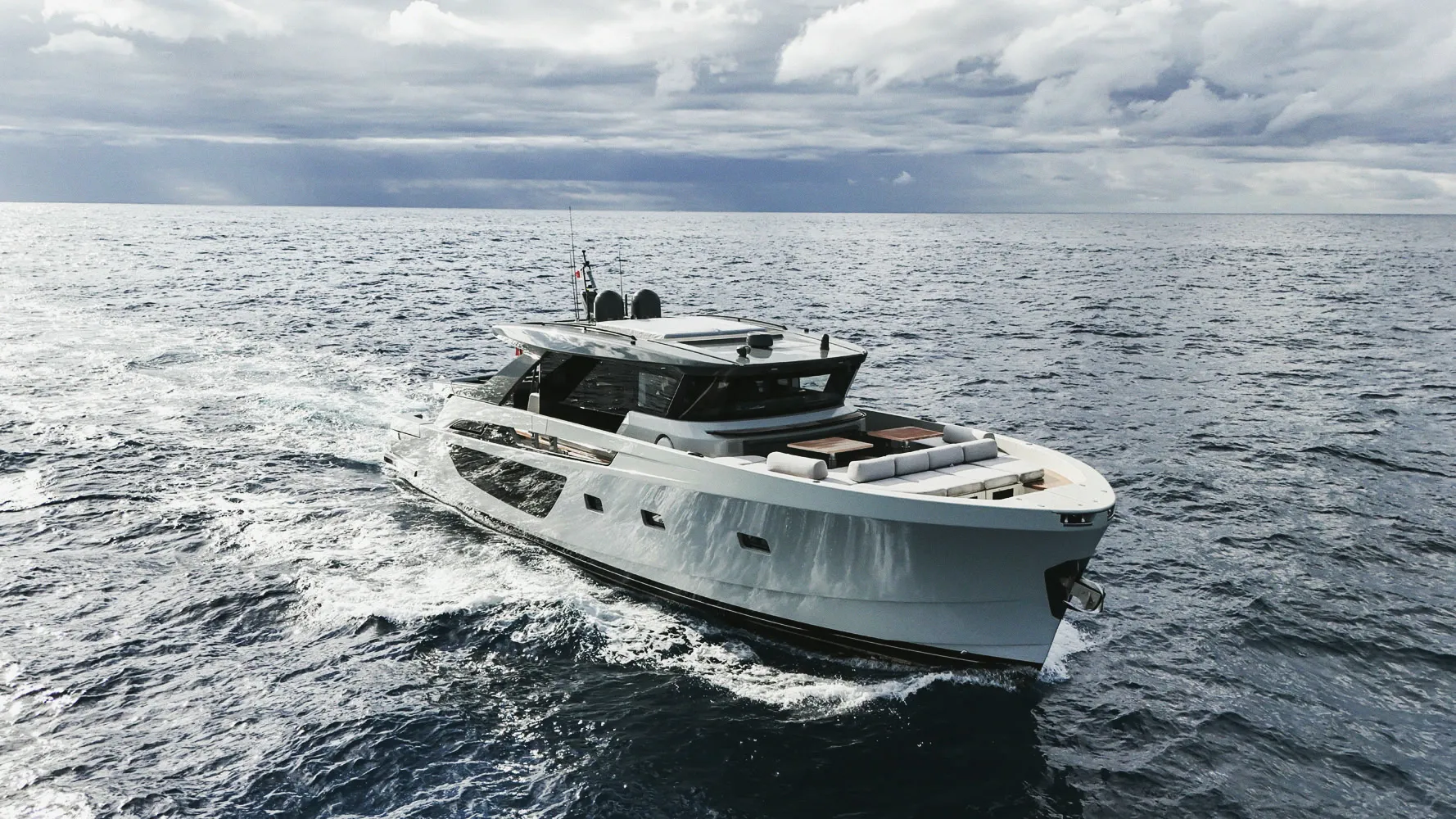 Le Blue Game 70 en navigation, vu de tribord : coque blanche, superstructure vitrée, mer formée.