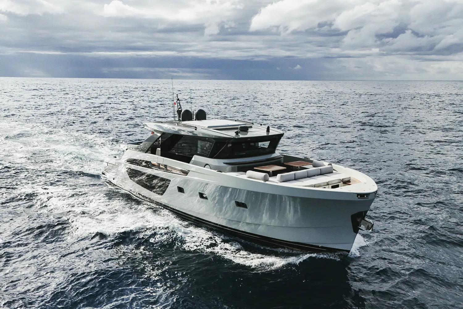 Le Blue Game 70 en navigation, vu de tribord : coque blanche, superstructure vitrée, mer formée.