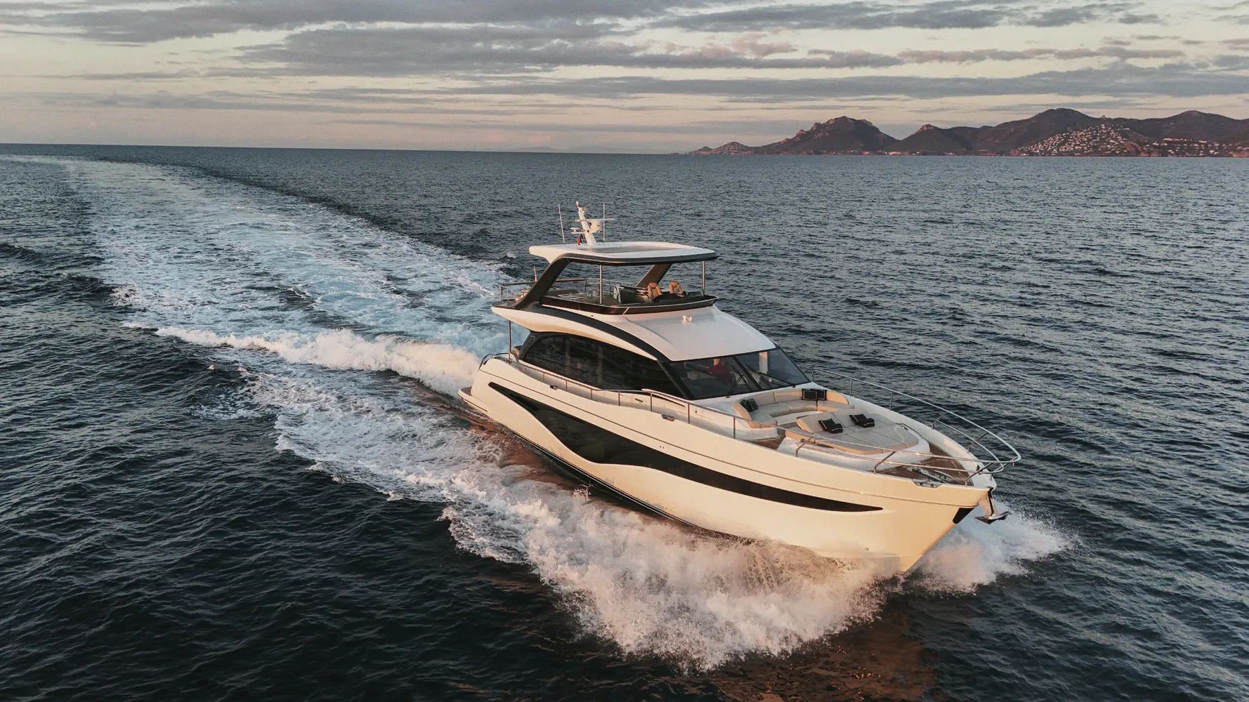 Le Princess Y72 en navigation vu du ciel, sillage et massif rouge à l'horizon.
