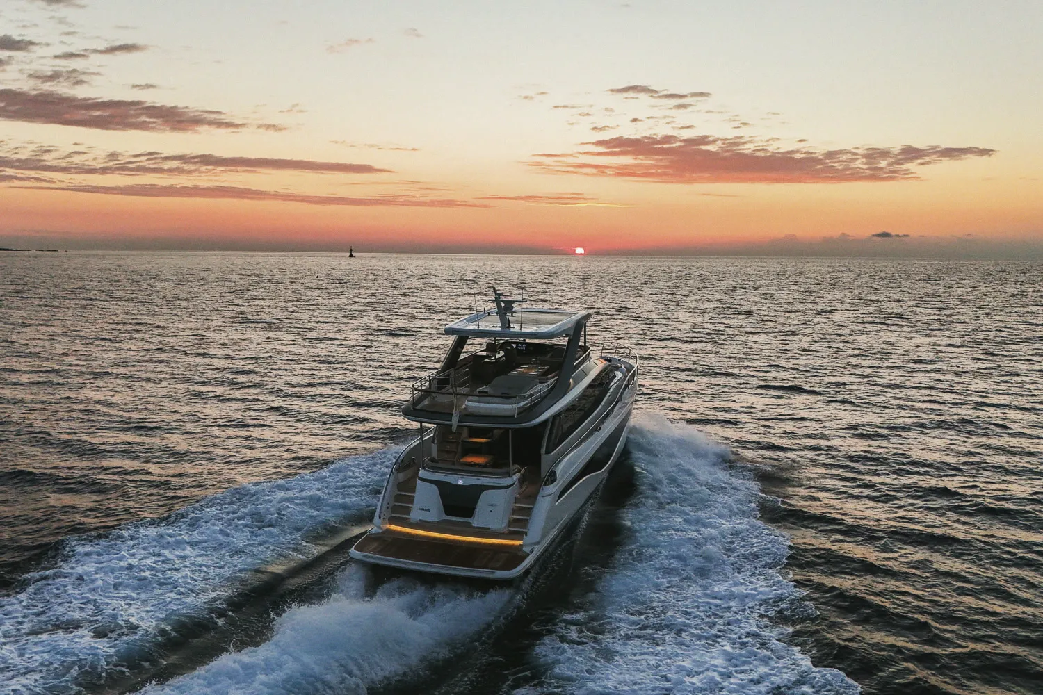 Le Princess Y72 en marche au coucher du soleil, mer et ciel orangés.