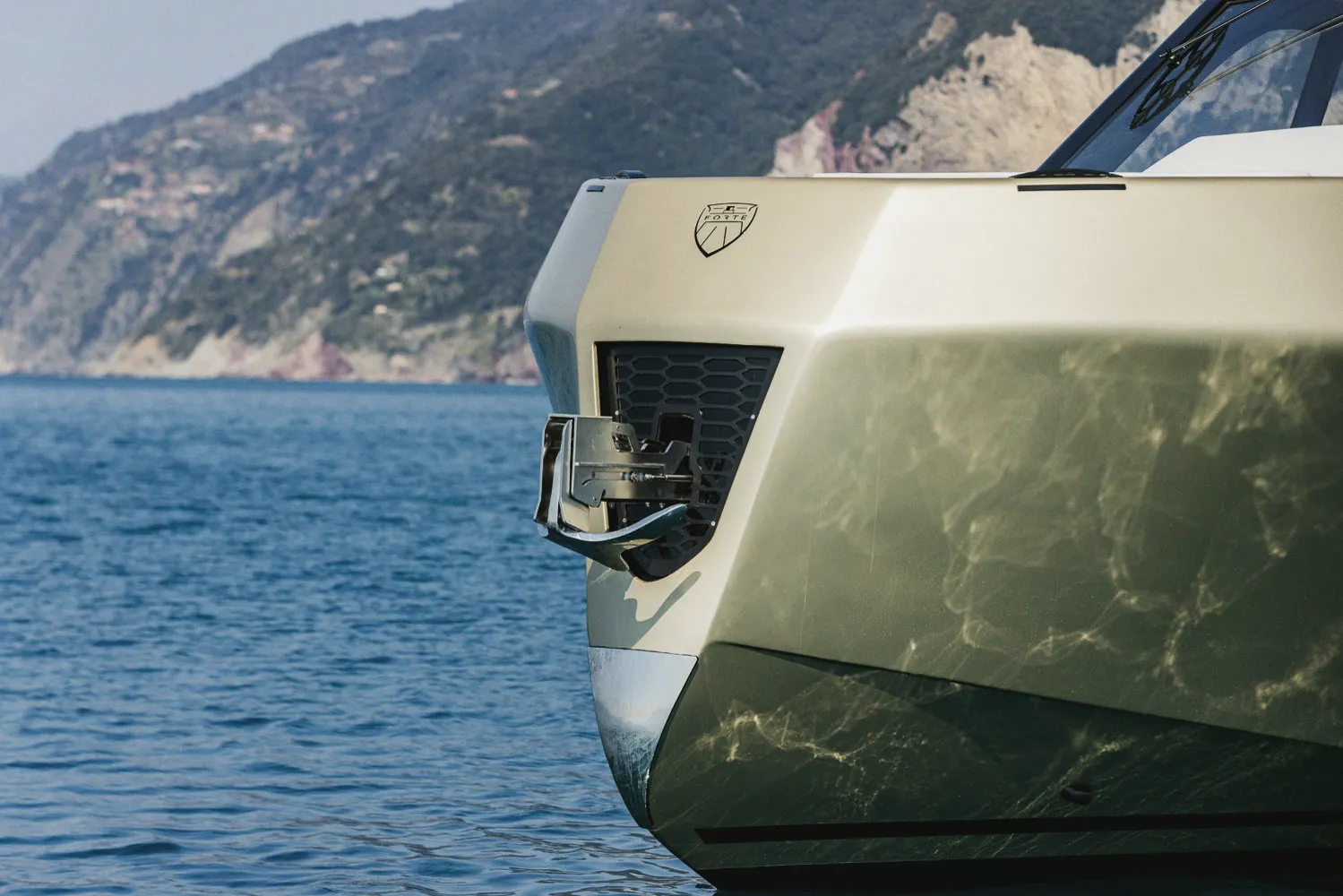 La proue vue de près : étrave anguleuse, écusson Forte et reflets sur la coque.