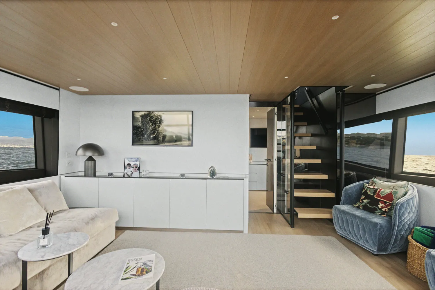 Le salon vu vers l'escalier de descente, plafond en bois clair et baies latérales.