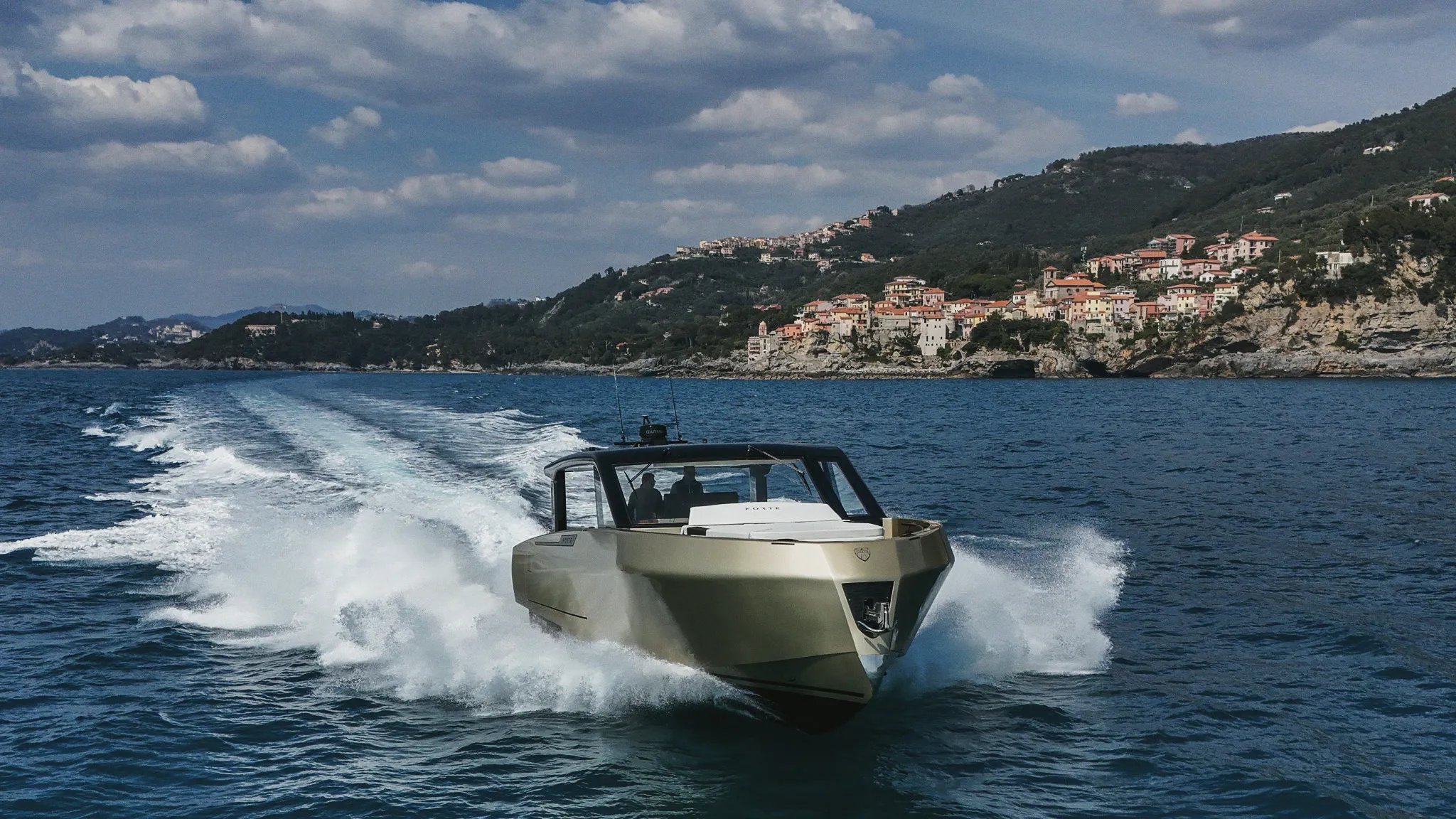 Un yacht Forte en navigation le long d'une côte, dans sa vague d'étrave.